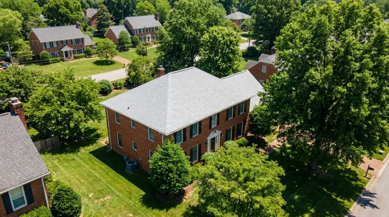 Aerial view of a two story brick house with a light gray shingle roof